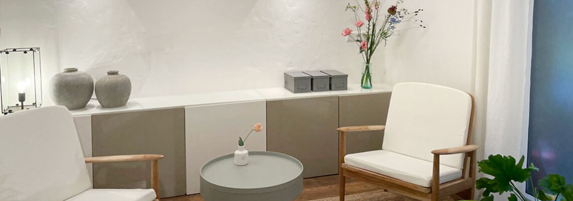 Altbauzimmer mit Sessel, Tisch und Sofa vor einem großen alten Bogenfenster
